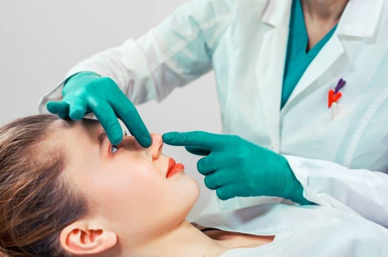 doctor with hands on patient's nose for rhinoplasty procedure.
