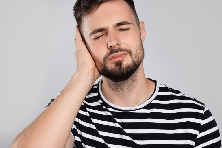 Man holds hand over ear