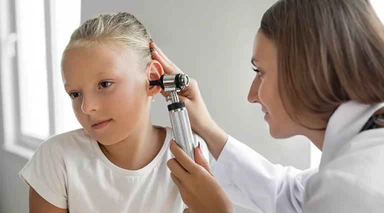 Girl having her ears examined by doctor